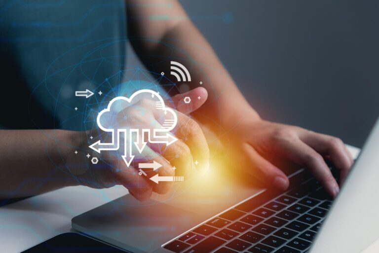 A cloud computing logo while a person in typing on his laptop